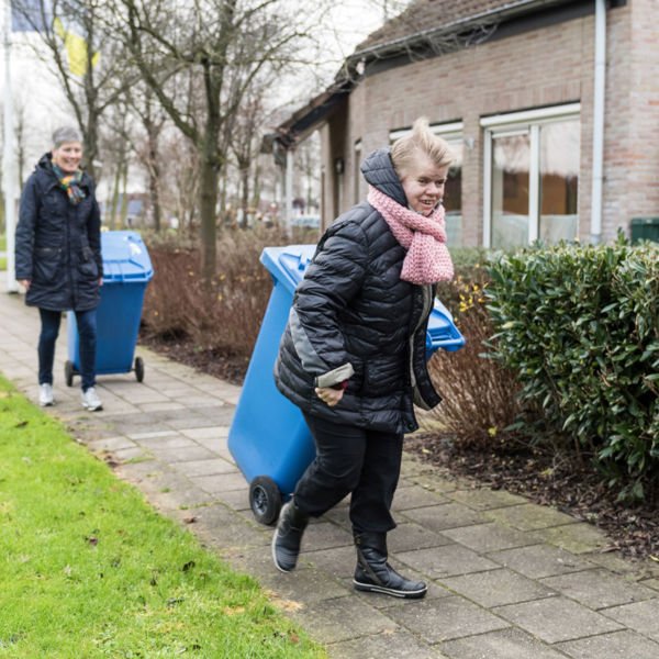 Vrouw zet een blauwe kliko aan de straat bij Visio in Emmen Vrouw zet een blauwe kliko aan de straat bij Visio in Emmen
