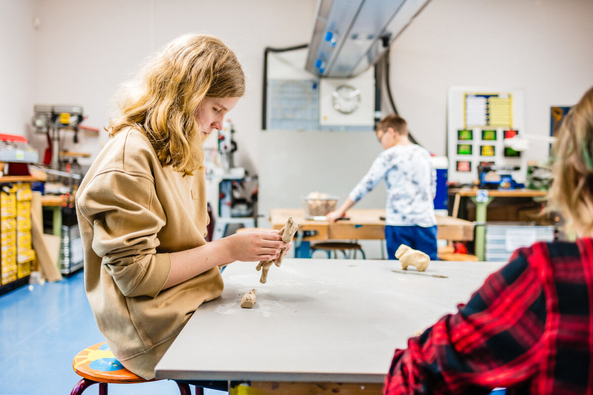 Meisje werkt met klei in een klaslokaal. 