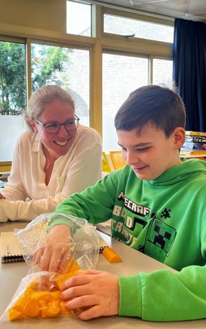 Dean met ambulant onderwijskundig begeleider van Visio aan tafel in een klaslokaal Dean met ambulant onderwijskundig begeleider van Visio aan tafel in een klaslokaal