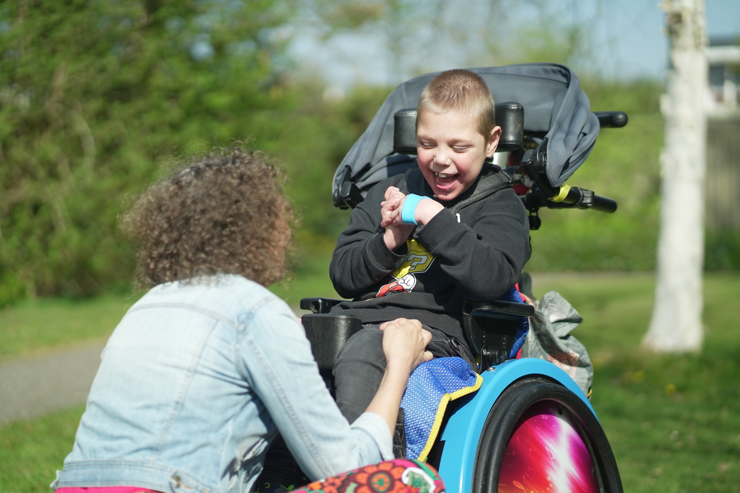 Medewerker en jonge cliënt met een meervoudige beperking in rolstoel