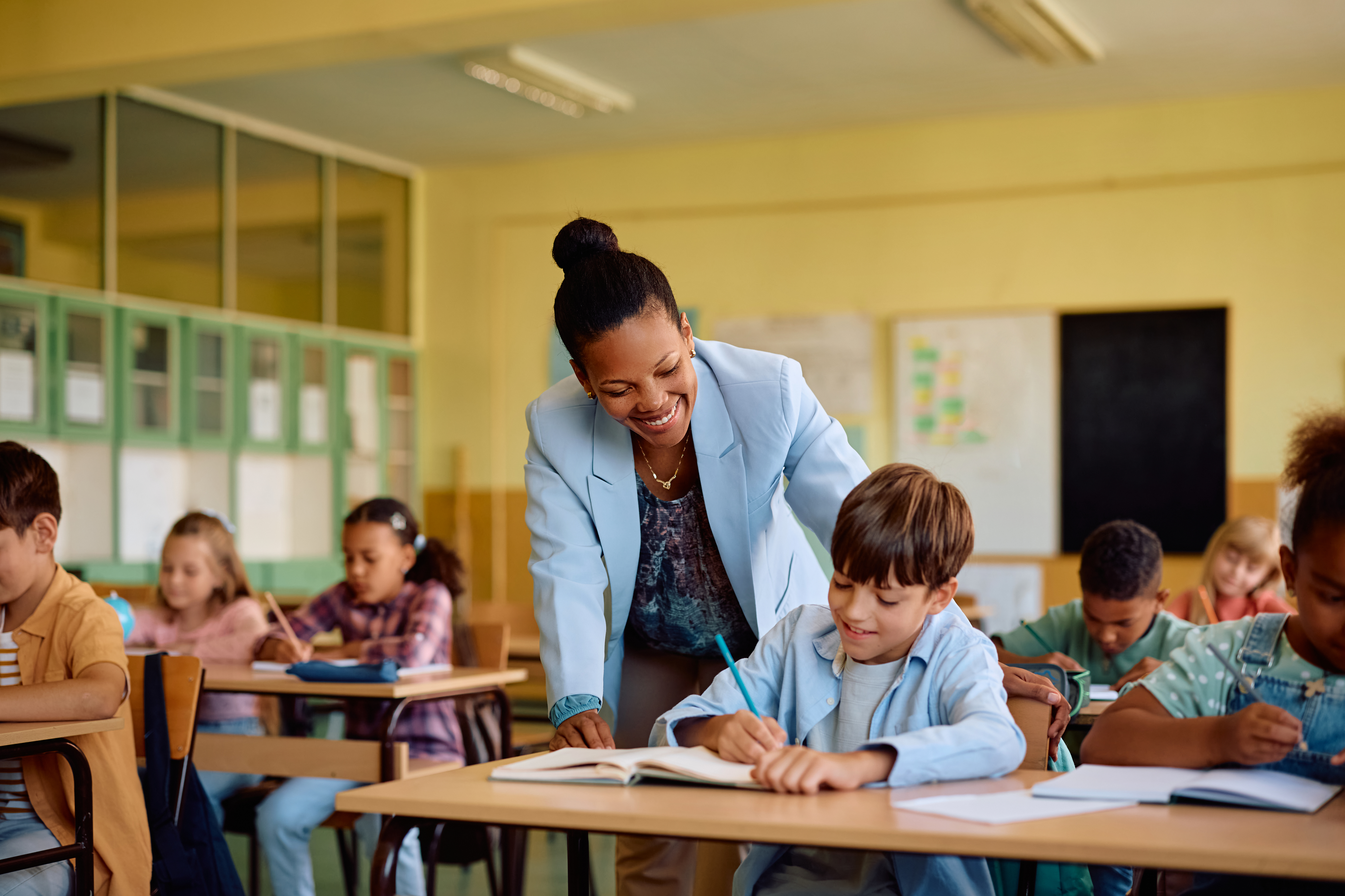Ambulante onderwijskundige begeleider helpt leerling aan bureau. 