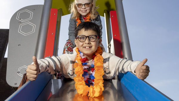 Twee kinderen, een jongen en een meisje, gaan samen van de glijbaan af. De jongen steekt zijn duimen omhoog. Twee kinderen, een jongen en een meisje, gaan samen van de glijbaan af. De jongen steekt zijn duimen omhoog.