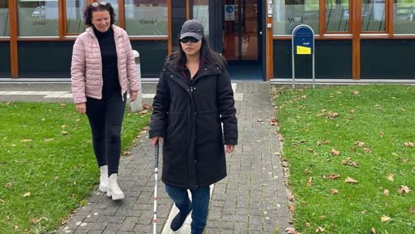 visio-het-loo-erf-Athittiya-Auaychai-loopt-met-stok-begeleid-door-medewerkerk.jpg (1) visio-het-loo-erf-Athittiya-Auaychai-loopt-met-stok-begeleid-door-medewerkerk.jpg (1)