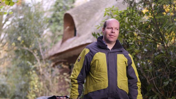 Cliënt brengt de post rond met een taststok in zijn hand en aan zijn andere hand een postwagentje Cliënt brengt de post rond met een taststok in zijn hand en aan zijn andere hand een postwagentje