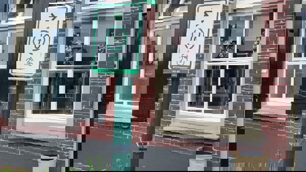 Een gebouw is te zien op de achtergrond. Op de voorgrond is een lantaarnpaal met een blauw straatnaambordje met "dorpstraat" erop. Op de paal zijn ook twee groen/witte bordjes van fietsroutes te zien. De bovenste wijst naar links en heeft het nummer 67, de onderste wijst naar rechts en heeft het nummer 10. Een gebouw is te zien op de achtergrond. Op de voorgrond is een lantaarnpaal met een blauw straatnaambordje met "dorpstraat" erop. Op de paal zijn ook twee groen/witte bordjes van fietsroutes te zien. De bovenste wijst naar links en heeft het nummer 67, de onderste wijst naar rechts en heeft het nummer 10.