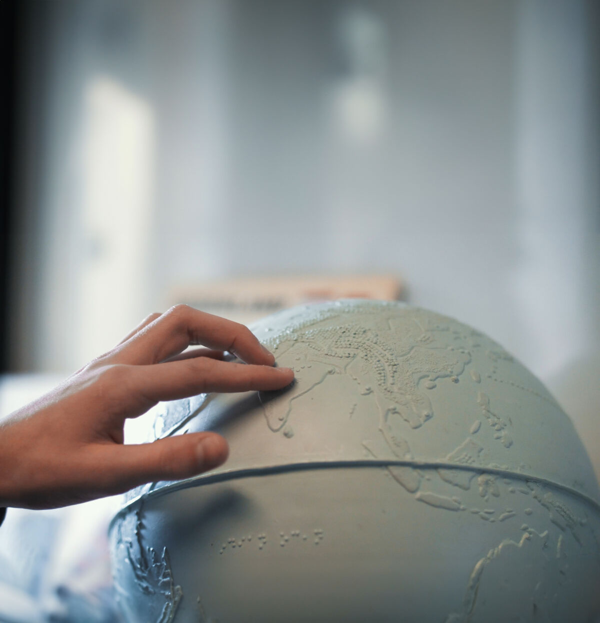 Een hand voelt aan een tactiele wereldbol. 