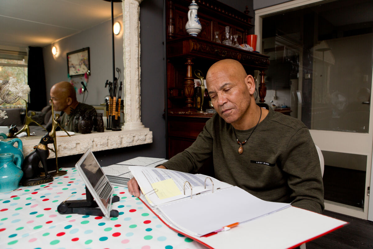 Man met een visuele beperking bladert aan tafel door een map met papieren