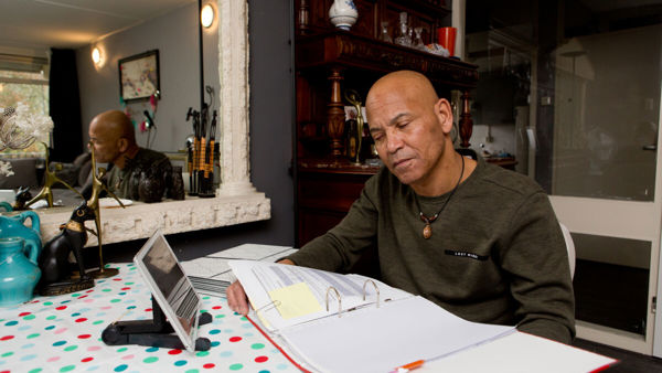 Man met een visuele beperking bladert aan tafel door een map met papieren Man met een visuele beperking bladert aan tafel door een map met papieren