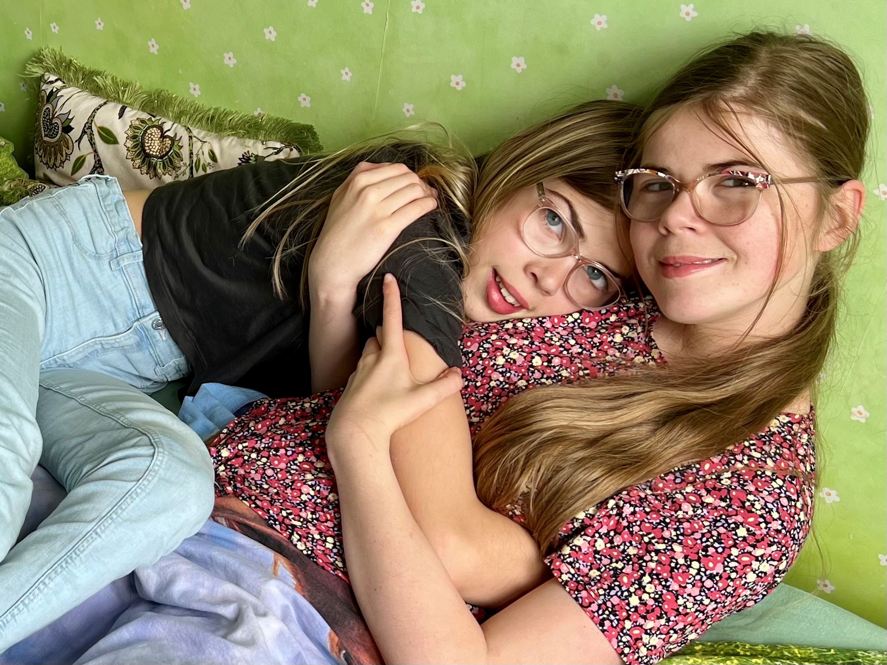 Norah en haar zus knuffelen op de bank. 