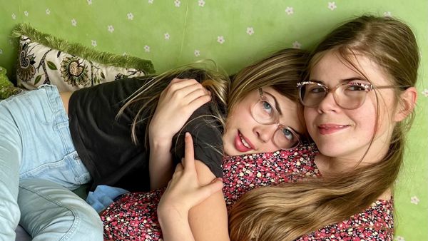 Norah en haar zus knuffelen op de bank. Norah en haar zus knuffelen op de bank.