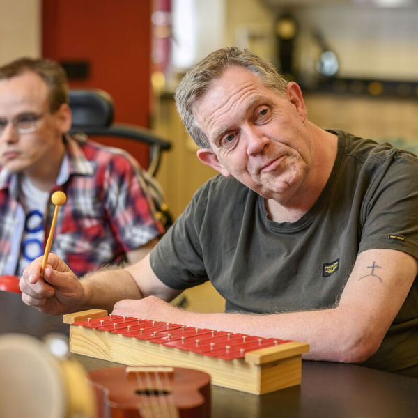 Cliënt met een visuele en verstandelijke beperking speelt op een xylofoon Cliënt met een visuele en verstandelijke beperking speelt op een xylofoon